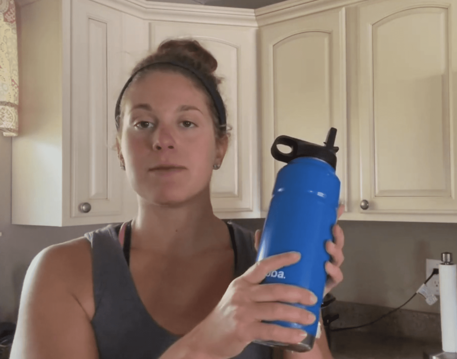 Woman holding up a blue bottle of water